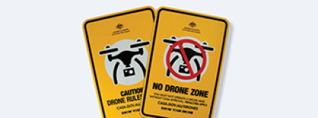 Two drone safety signs laying over a white background, partially overlapping each other