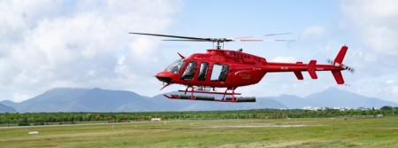 A red helicopter landing in a field