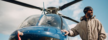 a male pilot standing in front of a rotary heli