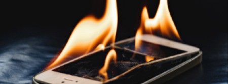 A cell phone on fire on a black background