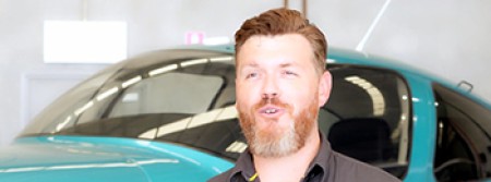 An aviation expert is interviewed in front of an aeroplane