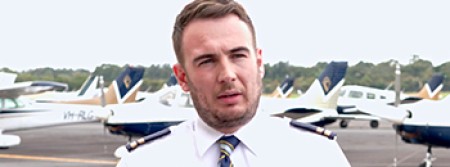 An aviation expert is interviewed on an airport apron, with aeroplanes parked behind him