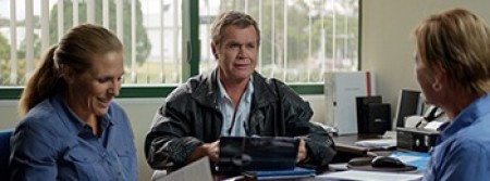 Three people sitting around a desk holding a meeting
