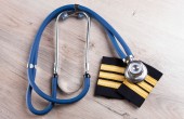 A stethoscope lies atop a pair of pilot's epaulettes on a table