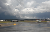 A wet airport taxiway under a cloudy sky