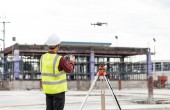 A drone with a man standing behind it holding the remote control for it