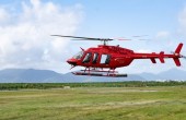 A red helicopter landing in a field