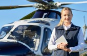 A female pilot standing in front of a helicopter