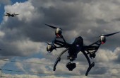 A drone flying against a cloudy sky with a passenger jet flying in the background