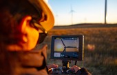 A female drone pilot flying a drone to inspect wind turbines