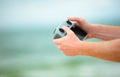 A person's hands holding a drone remote control in front of a blurry background