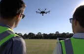 Two men in high-visibility jackets flying a drone