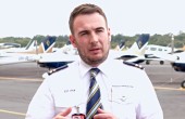 An aviation expert is interviewed on an airport apron, with aeroplanes parked behind him