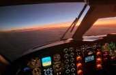 View from a cockpit in flight looking out over a sunset.