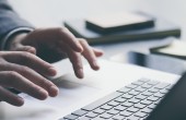 A person's hands typing on the keyboard of a laptop