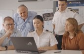 Several staff members gather around a pilot working on a laptop