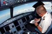 A pilot fills out documentation in the cockpit of a flying aircraft