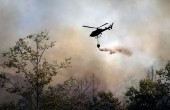 A helicopter drops water on a bushfire