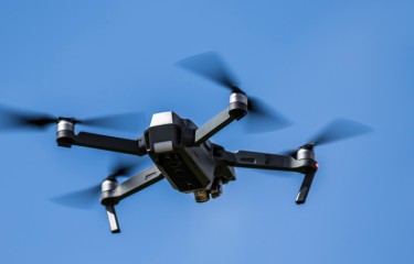 A quadcopter drone flying in a cloudless blue sky