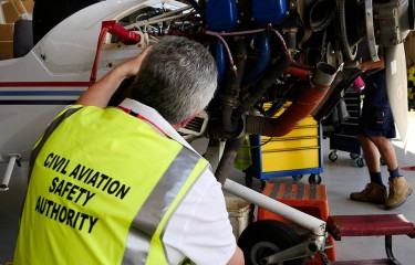 A CASA inspector examining an engine being maintained