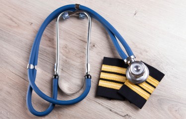 A stethoscope lies atop a pair of pilot's epaulettes on a table
