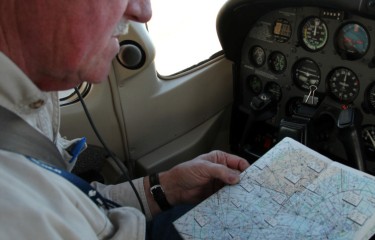 A flight examiner sitting in the cockpit of a plane, reading a map