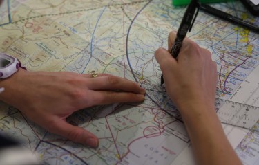 A pair of hands measuring a line on a map using a transparent ruler.