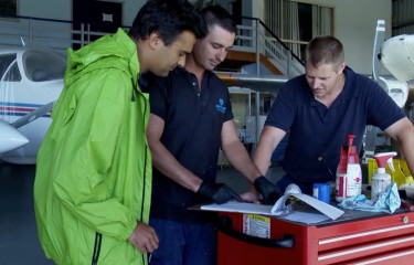 A group of engineers reviewing documents on top of a toolbox in a hangar