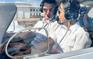 A male and female pilot talking to each other in the cockpit of an aeroplane