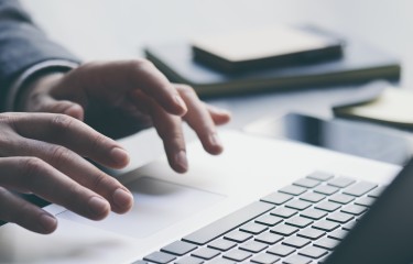 A person's hands typing on the keyboard of a laptop