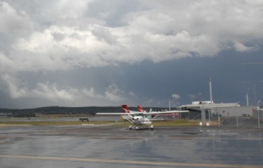 An aeroplane is parked on the apron of an airport on a cloudy day