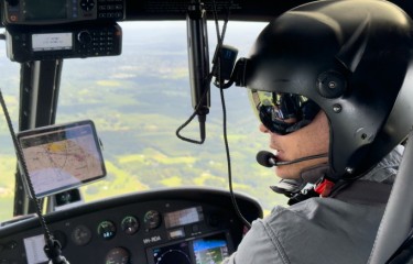 A pilot wearing a helmet flying over the countryside