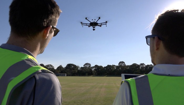 A pair of RPAS operators in high-vis vests flying a drone