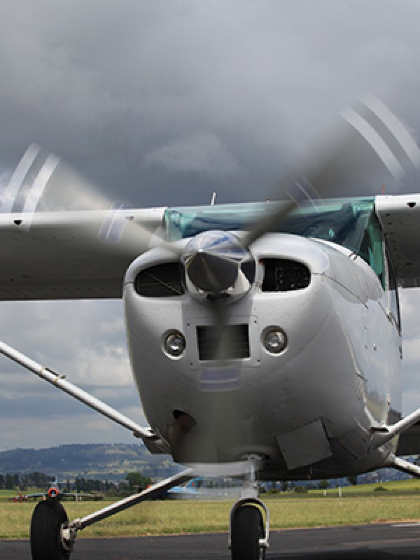 A small plane sitting on a taxiway as a storm fills the sky behind it