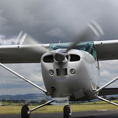 A small plane sitting on a taxiway as a storm fills the sky behind it